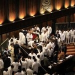 For the second day, Parliamentary proceedings were disrupted by Members of Parliament. On Wednesday, they protested the vote of no confidence being moved against Mahinda Rajapaksa, who was appointed Prime Minister by President Sirisena. Pictured here are attempts to protect the Speaker on Thursday, when some Parliamentarians attempted to surround him, soon after Rajapaksa addressed Parliament. (Photo credit courtesy Twitter)